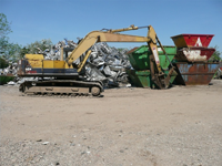 Digger in front of skips and scrap metal